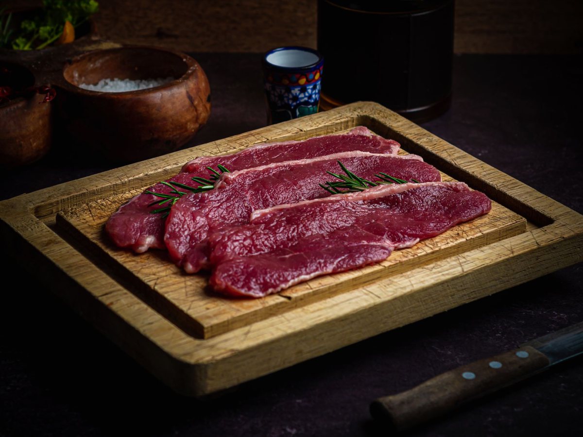 木のまな板の上で切り分けられた黒毛和牛の赤身