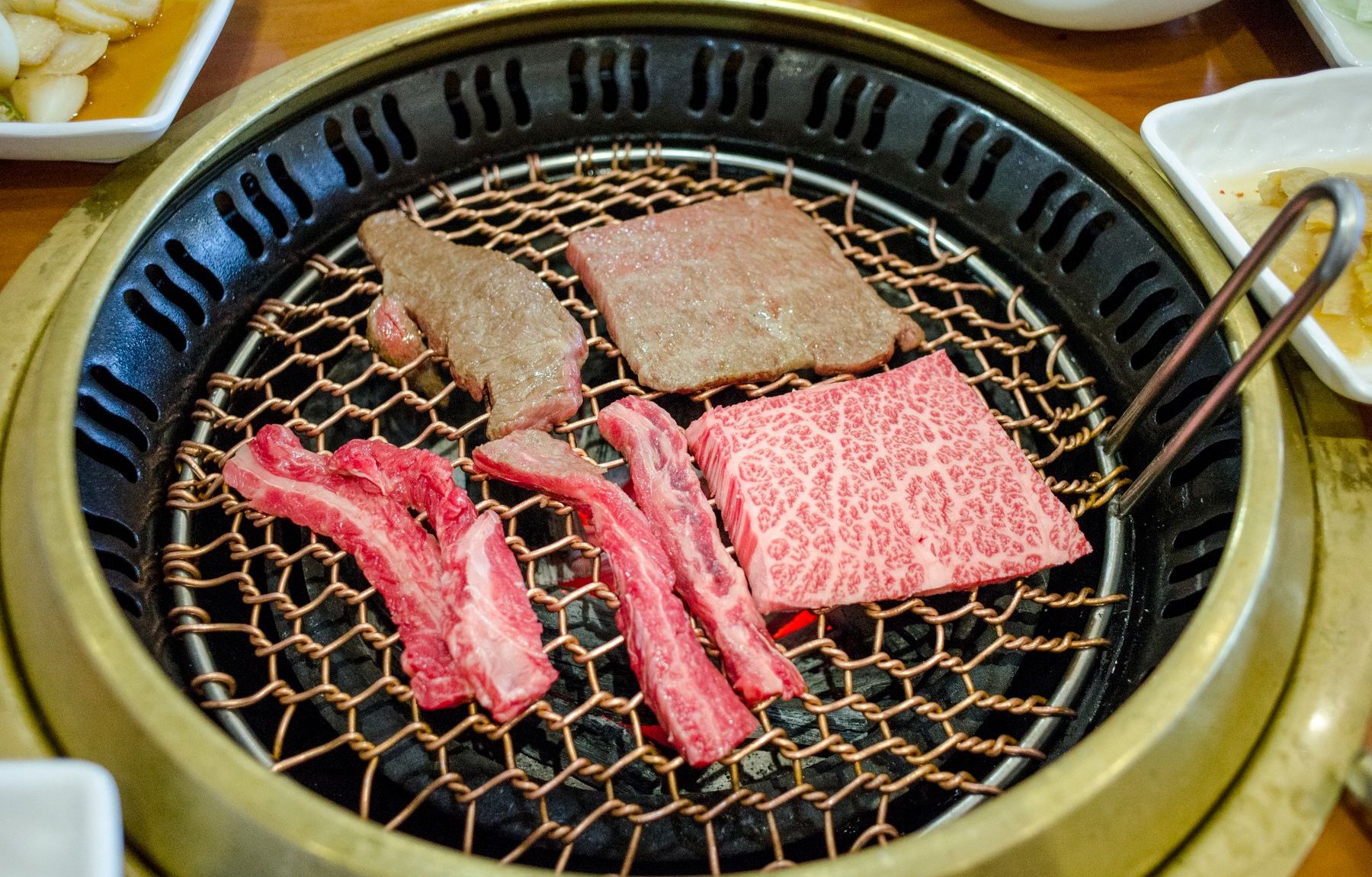 炭火の網の上で焼かれる黒毛和牛のタン・カルビ・ロース